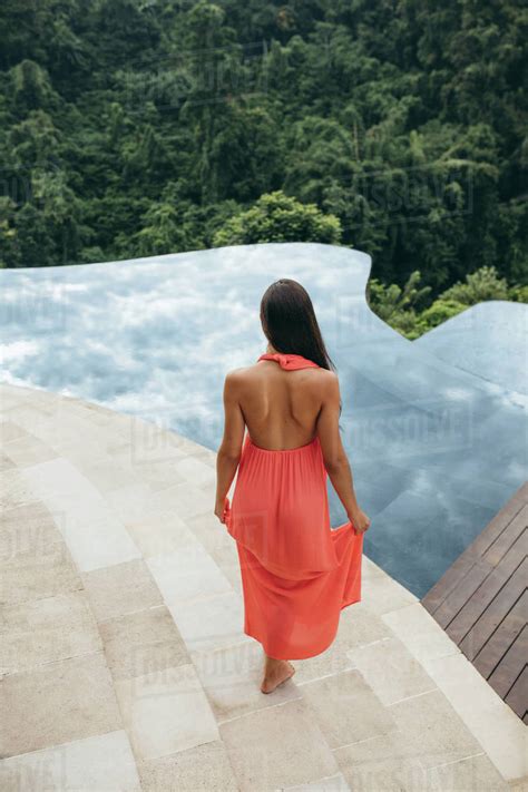 Rear View Shot Of Young Woman Walking Towards Swimming Pool At Luxury
