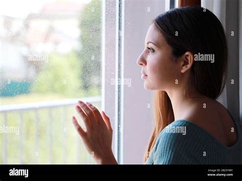 Melancholic Sad Young Woman Looking Through The Window At Home In A