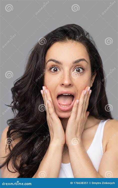 Pretty Brunette Girl Touching Her Face And Looking Shocked Stock Image