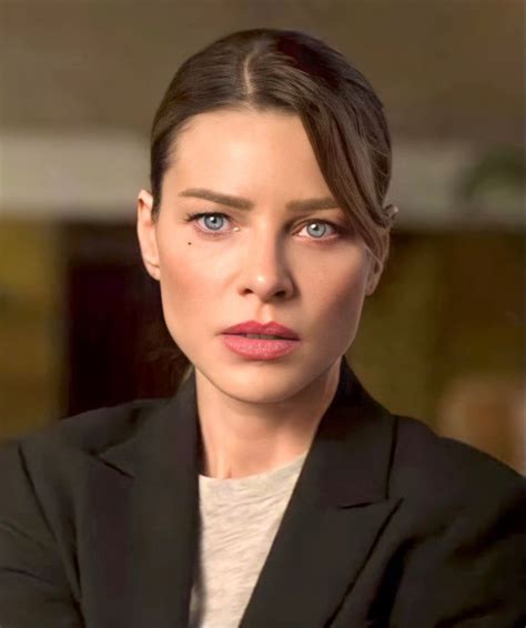 A Woman With Blue Eyes Is Looking At The Camera While Wearing A Black Suit And White Shirt
