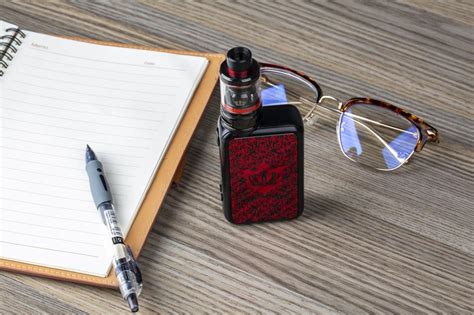 Beautiful Red And Black Uwell Vape Glasses And Notebook With Pen On The Wooden Surface Free