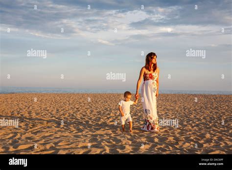 La Madre Y El Niño Caminando Por La Playa Tomados De Las Manos