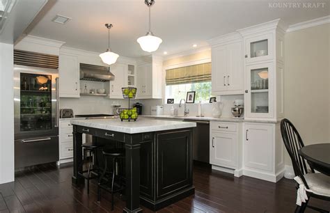 A kitchen island may only have cabinetry on one of its longer sides if there is a breakfast bar counter attached to the other side. Black Kitchen Island and White Cabinets in Chatham, NJ