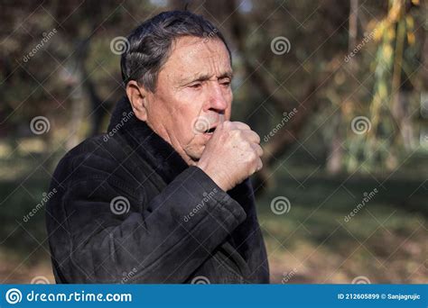 Portrait Of A Coughing Senior Man Outdoors Looking Down Stock Image