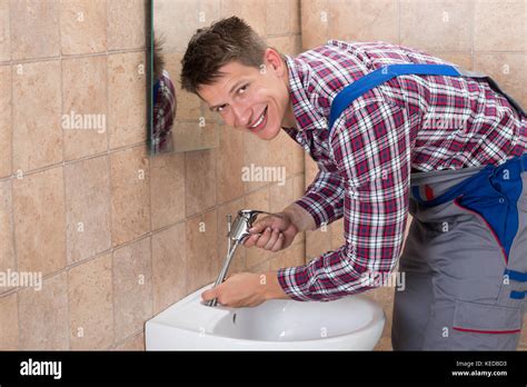 Young Male Plumber Hand Fixing Tap Of Sink In Bathroom Stock Photo Alamy