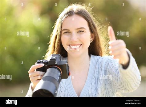 Front View Portrait Of A Happy Photographer Holding Mirrorless Camera
