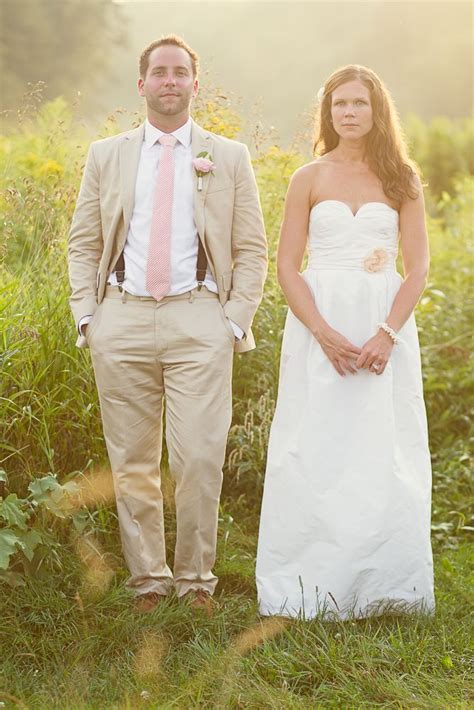 A Bride And Groom Standing In The Grass