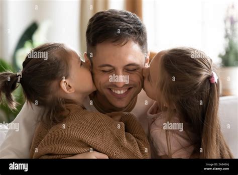Cute Daughters Kissing Dad On Cheeks Congratulating With Fathers Day