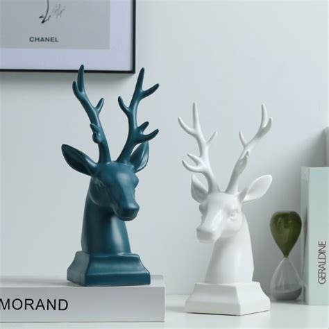 Two White And Blue Deer Head Statues On A Table Next To Each Other One