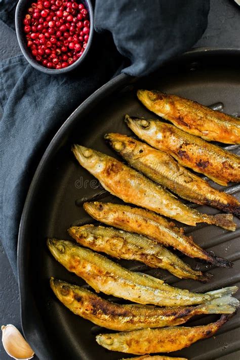 Fried Smelt In The Pan On The Table With Tomatoes And Pepper Black
