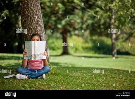 Happy Young Girl Reading A Book Under A Tree Stock Photo Alamy