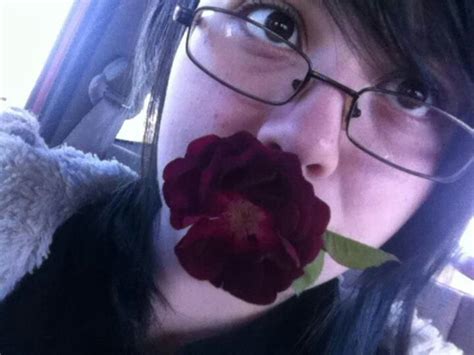 A Woman With Glasses And A Fake Flower In Her Mouth