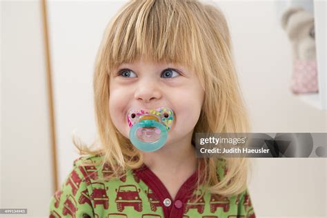 Portrait Of Happy 2 Year Old Girl With Pacifier High Res Stock Photo