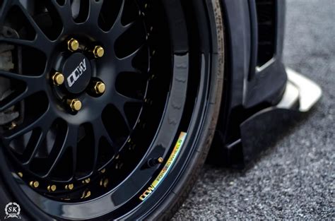 The Front Wheel Of A Black Sports Car With Gold Spokes And Wheels On It