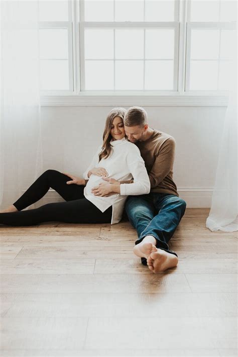 A Man And Woman Sitting On The Floor In Front Of A Window With Their