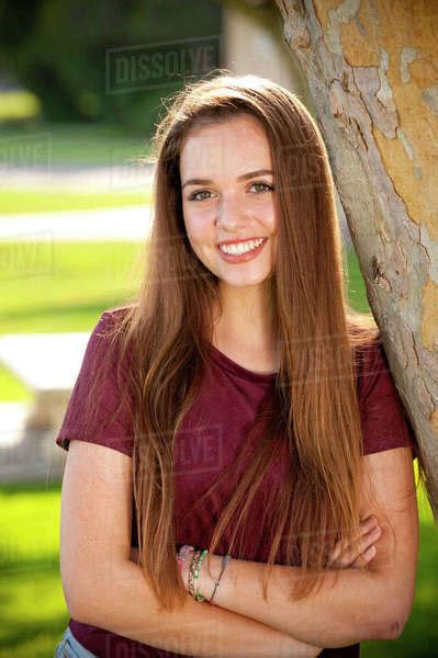Portrait Of Smiling Teenage Girl Leaning On Tree Stock Photo Dissolve