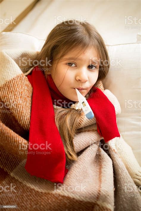 Little Girl Lying In Bed And Holding Thermometer In Mouth Stock Photo