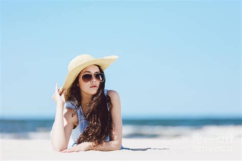 Pretty Girl Laying On The Beach Wearing Hat And Sunglasses Photograph