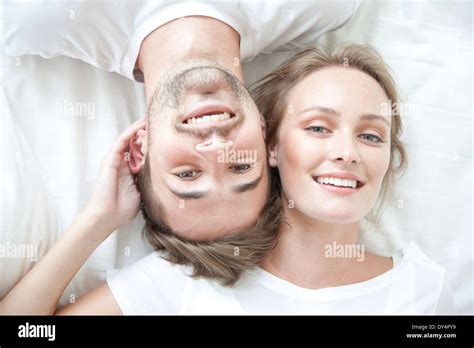Smiling Couple Lying On Bed Facing Opposite Directions Stock Photo Alamy