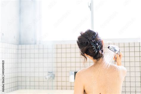 Foto Stock お風呂でシャワーを浴びる若い女性 Adobe Stock