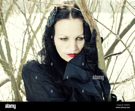 Woman Dressed In A Gothic Style Romantic Gothic Standing In Front Of A Bush Looking Serious