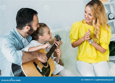 Padre E Hija Que Tocan La Guitarra Para La Madre En Casa Mientras Que