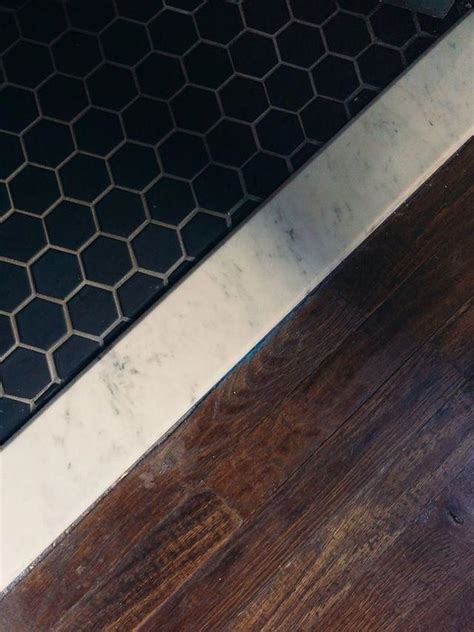 A Close Up Of A Wooden Floor With Black And White Tiles On The Bottom Half