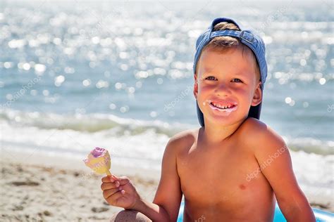 niño con helado en la playa sentado en tubo de agua