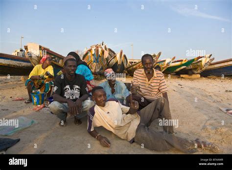 A Group Of Men Pose In Front Of The Colorfully Painted Fishing Boats