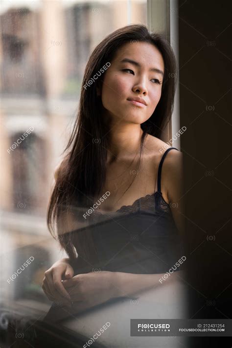 Portrait Of Beautiful Chinese Woman Indoors Next To A Window With Natural Light Happy