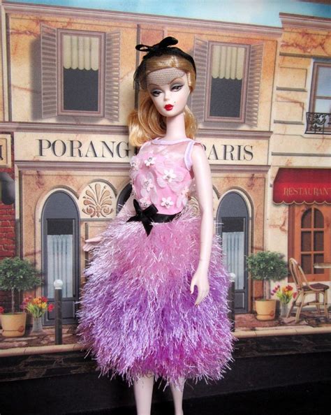 A Barbie Doll Wearing A Pink And Purple Dress With Feathers On Its Skirt