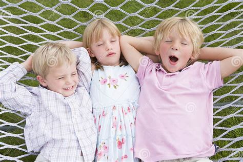 Tres Niños Que Se Relajan Y Que Duermen En Hamaca Foto De Archivo