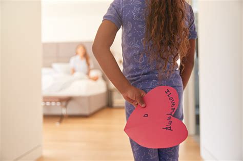 Hispanic Girl Surprising Mother In Bedroom With Homemade Card For