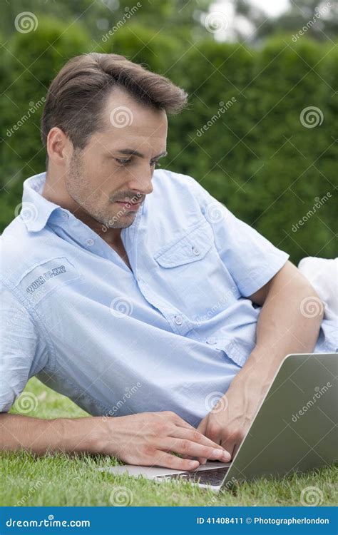 Young Man Using Laptop While Lying On Grass In Park Stock Image Image Of Lifestyle Connection