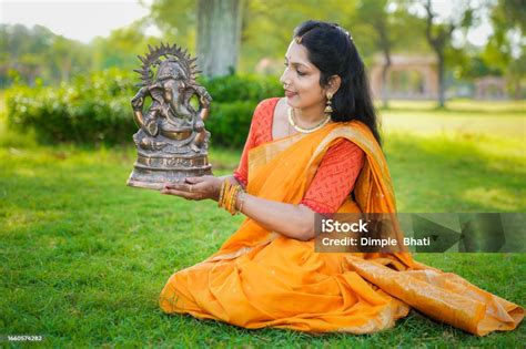 Glückliche Junge Indische Frau Mit Sari Sitzt Und Hält Lord Ganeshaidol Im Freien Im Park Um Das