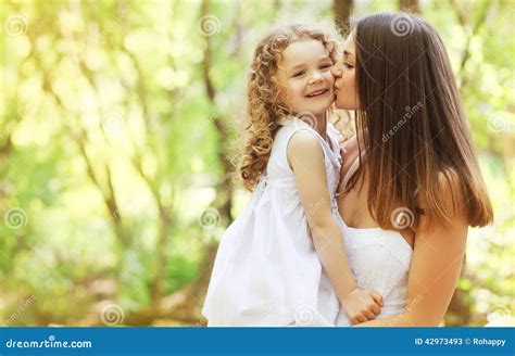 Madre Feliz Que Besa A La Hija Que Camina En El Parque Imagen De