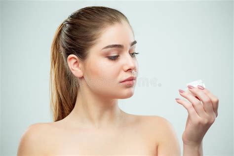 Portrait Of Young Beautiful Woman Applying Moisturizing Cream On Her