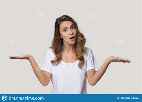 Confused Attractive Young Woman Shrugging Shoulders Looking At Camera