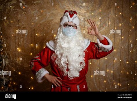 Santa Claus Posing In A Mask On A Wall Background With A Garland Shows