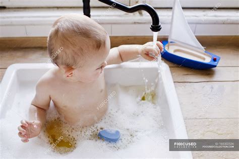 Baby Boy Bathing In Kitchen Sink Touching Running Water — Hygiene