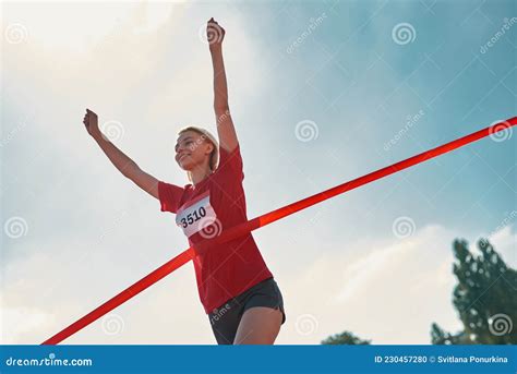 Low Angle View Of Happy Young Female Runner With Arms Raised Reaching