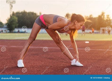 Side View Of Athletic Woman Working Out In Stadium Bending And