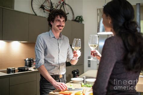 couple preparing dinner and drinking white wine photograph by caia image science photo library