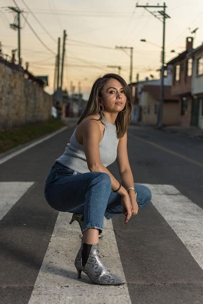 premium photo pretty latin single woman portrait outdoors wearing jeans squatting over