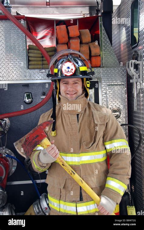 Male Firefighter Holding Ax In Front Of Fire Truck Wearing Bunker Gear