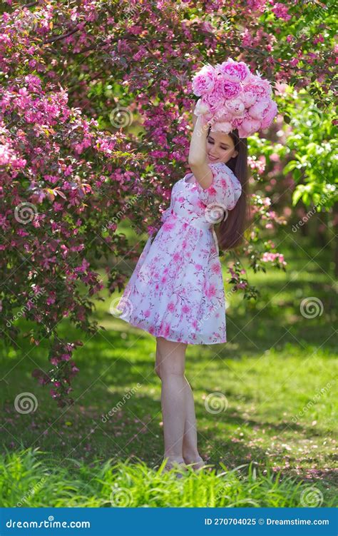 A Happy Girl In A Light Pink Dress Holding A Bouquet Of Large Pink