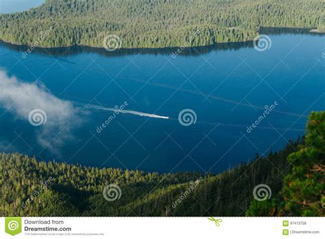 Lone Boat Sailing On Blue Water Between Two Islands With Forest Stock