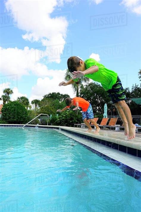 Two Boys Jumping In A Swimming Pool Stock Photo Dissolve