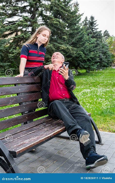 Portrait Of Happy Granddaughter And Grandfather Sitting On A Bench