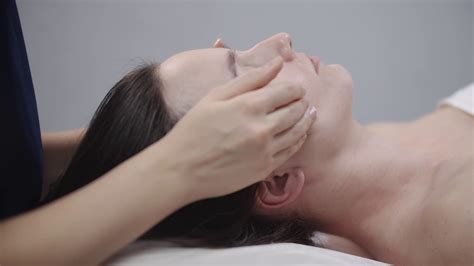 Woman Massagist Doing A Face Massage Using Her Fingers On The Clean Skin Of Her Female Client